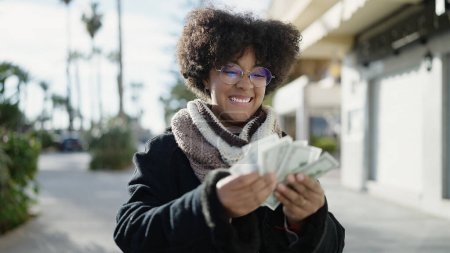 Photo for Young african american woman smiling confident counting dollars at street - Royalty Free Image