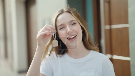 Téléchargez les photos : Young caucasian woman smiling confident holding key of new home at street - en image libre de droit