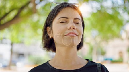 Photo for Young beautiful hispanic woman breathing with closed eyes at park - Royalty Free Image