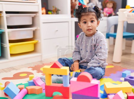 Photo for Adorable hispanic girl playing with construction blocks sitting on floor at kindergarten - Royalty Free Image