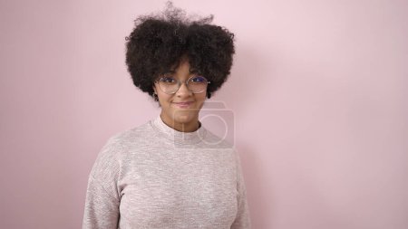 Foto de Joven mujer afroamericana sonriendo confiada de pie sobre un fondo rosa aislado - Imagen libre de derechos