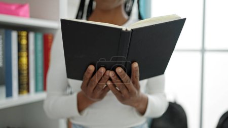 Photo for African american woman student reading book standing at university classroom - Royalty Free Image