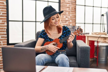 Téléchargez les photos : Jeune femme caucasienne musicien souriant confiant jouer ukulele au studio de musique - en image libre de droit