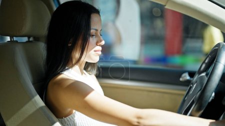 Photo for Young beautiful hispanic woman driving car with relaxed face at street - Royalty Free Image