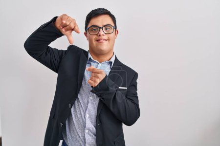 Foto de Joven hombre hispano con síndrome de Down con estilo de negocio sonriente haciendo marco con manos y dedos con cara feliz. concepto de creatividad y fotografía. - Imagen libre de derechos