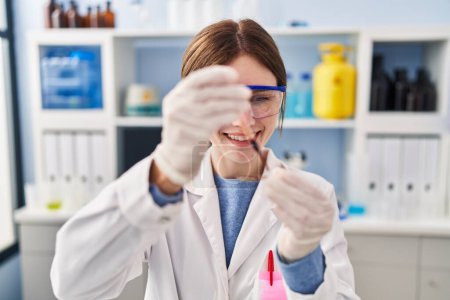 Foto de Joven mujer rubia científica derramando sangre en la muestra en el laboratorio - Imagen libre de derechos