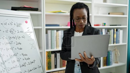 Foto de Profesora afroamericana dando clases de matemáticas usando laptop en el aula universitaria - Imagen libre de derechos