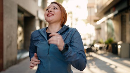 Photo for Young redhead woman wearing sportswear running at street - Royalty Free Image