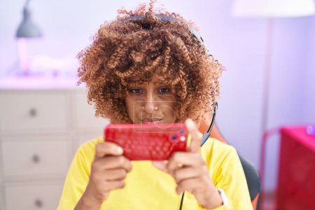 Foto de Streamer mujer afroamericana jugando videojuegos con smartphone en la sala de juegos - Imagen libre de derechos