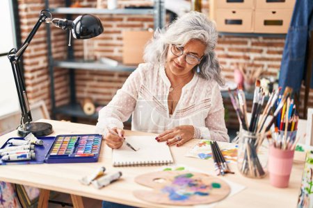 Photo for Middle age woman artist drawing on notebook at art studio - Royalty Free Image