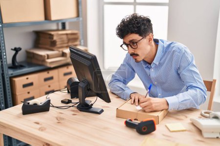Photo for Young caucasian man ecommerce business worker writing on package at office - Royalty Free Image