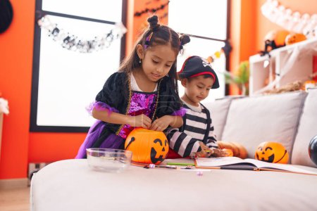 Foto de Adorable chico y chica teniendo fiesta de halloween sosteniendo caramelos en casa - Imagen libre de derechos