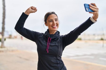 Téléchargez les photos : Jeune femme hispanique faire un geste fort faire selfie par le smartphone à la rue - en image libre de droit