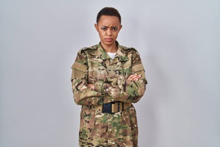 Foto de Hermosa mujer afroamericana vistiendo camuflaje ejército uniforme escéptico y nervioso, desaprobando la expresión en la cara con los brazos cruzados. persona negativa. - Imagen libre de derechos