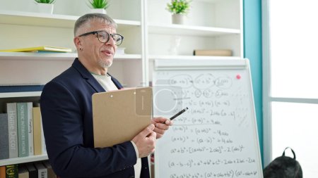 Foto de Hombre de pelo gris de mediana edad que enseña matemáticas en el aula universitaria - Imagen libre de derechos