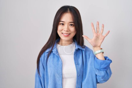 Téléchargez les photos : Jeune femme chinoise debout sur fond blanc montrant et pointant vers le haut avec les doigts numéro cinq tout en souriant confiant et heureux. - en image libre de droit