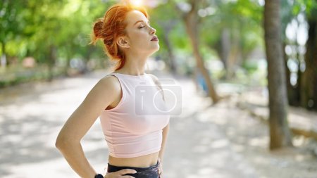 Photo for Young redhead woman wearing sportswear breathing at park - Royalty Free Image