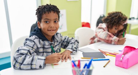 Téléchargez les photos : Adorables étudiants afro-américains garçons et filles souriants dessin confiant sur ordinateur portable en classe - en image libre de droit