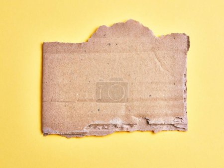 Photo for One ripped piece of cardboard material over isolated yellow background - Royalty Free Image