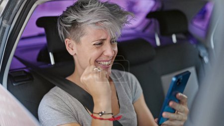 Foto de Joven pasajera sentada en coche usando smartphone celebrando en la calle - Imagen libre de derechos