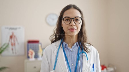 Photo for Young beautiful hispanic woman doctor standing with serious expression at clinic - Royalty Free Image