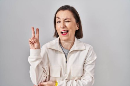Téléchargez les photos : Femme hispanique du Moyen Age debout sur fond isolé souriant avec un sourire heureux clin d'oeil à la caméra faisant signe de victoire avec les doigts. numéro deux. - en image libre de droit
