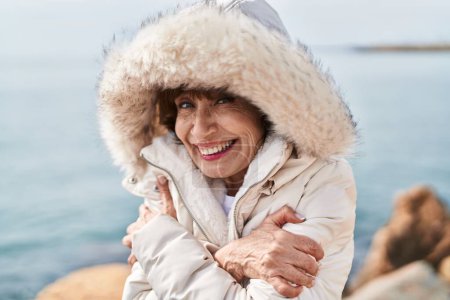 Téléchargez les photos : Middle age woman smiling confident freezing at seaside - en image libre de droit
