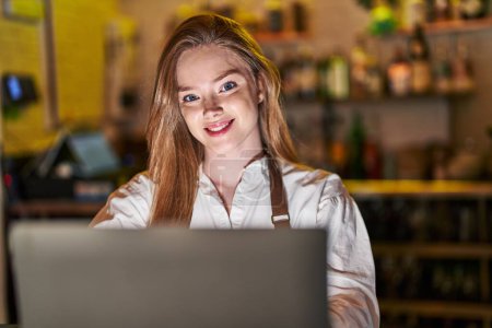 Foto de Young caucasian woman waitress smiling confident using laptop at restaurant - Imagen libre de derechos