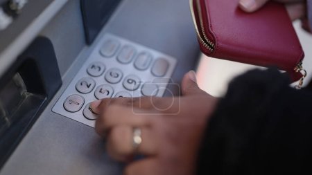 Téléchargez les photos : Jeune femme afro-américaine appuyant sur le mot de passe pin sur le distributeur de billets de banque à la rue - en image libre de droit