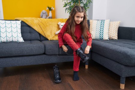 Photo for Adorable hispanic girl sitting on the sofa wearing shoes at home - Royalty Free Image