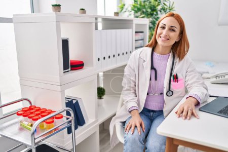 Téléchargez les photos : Jeune femme caucasienne médecin en utilisant un ordinateur portable assis sur la table à la clinique - en image libre de droit