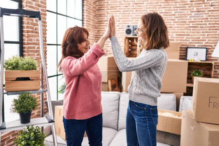 Photo for Two women mother and daughter high five with hands raised up at new home - Royalty Free Image