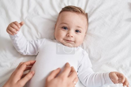 Adorable caucasian baby smiling confident for tickles at bedroom