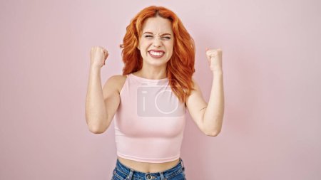 Photo for Young redhead woman smiling confident standing with winner expression over isolated pink background - Royalty Free Image