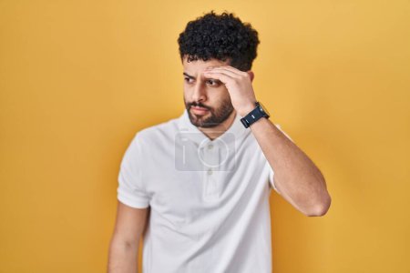 Photo for Arab man standing over yellow background worried and stressed about a problem with hand on forehead, nervous and anxious for crisis - Royalty Free Image