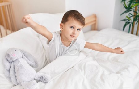 Photo for Adorable caucasian boy waking up stretching arms at bedroom - Royalty Free Image