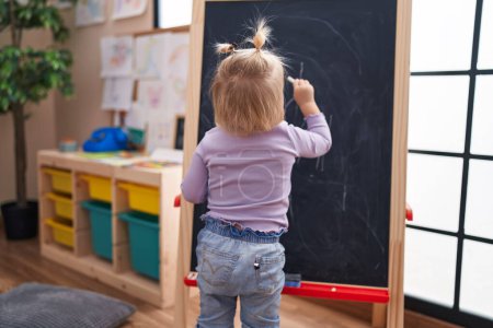 Photo for Adorable blonde girl preschool student drawing on blackboard at kindergarten - Royalty Free Image