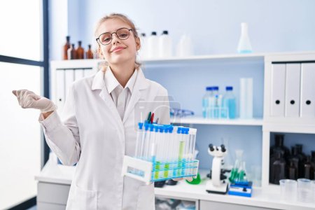 Photo for Young caucasian woman working at scientist laboratory holding samples screaming proud, celebrating victory and success very excited with raised arm - Royalty Free Image