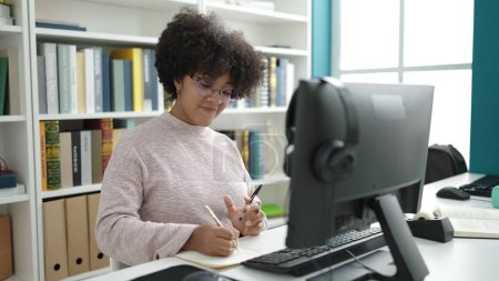 Téléchargez les photos : Jeune étudiante afro-américaine utilisant l'écriture informatique sur ordinateur portable dans une salle de classe universitaire - en image libre de droit
