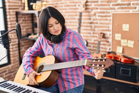 Photo for Young chinese woman musician playing guitar at music studio - Royalty Free Image
