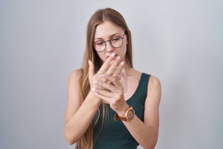 Foto de Mujer joven caucásica de pie sobre fondo blanco sufriendo dolor en las manos y los dedos, inflamación de la artritis - Imagen libre de derechos