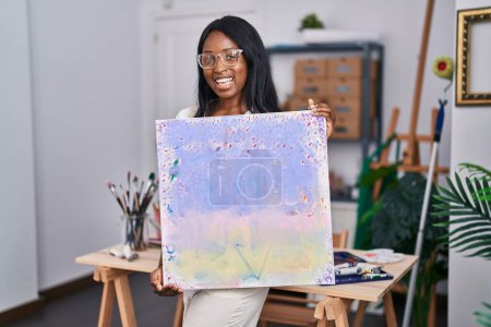 Téléchargez les photos : Jeune artiste afro-américaine souriante tenant tirage au sort au studio d'art - en image libre de droit