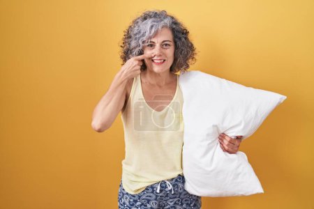 Photo for Middle age woman with grey hair wearing pijama hugging pillow pointing with hand finger to face and nose, smiling cheerful. beauty concept - Royalty Free Image