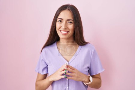 Téléchargez les photos : Jeune femme hispanique avec les cheveux longs debout sur fond rose mains ensemble et doigts croisés souriant détendu et joyeux. succès et optimisme - en image libre de droit