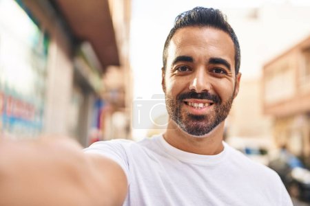 Photo for Young hispanic man smiling confident making selfie by the camera at street - Royalty Free Image