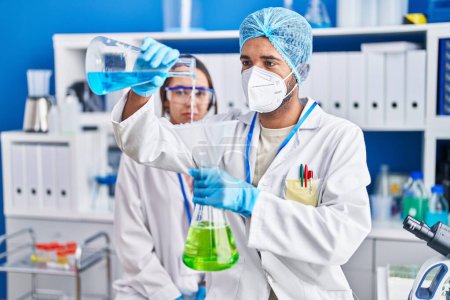 Téléchargez les photos : Man and woman scientists pouring liquid on test tube at laboratory - en image libre de droit