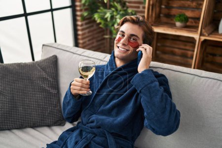 Téléchargez les photos : Young caucasian man wearing under eye patches talking on smartphone at home - en image libre de droit