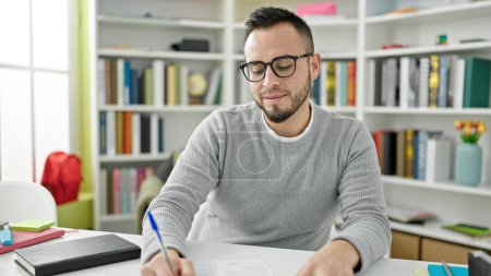 Photo for Hispanic man student writing on notebook at library university - Royalty Free Image