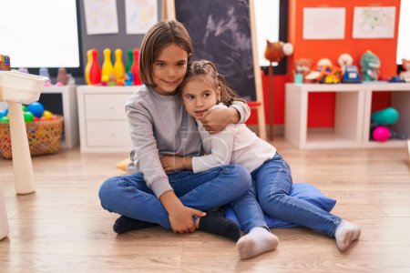 Photo for Adorable boy and girl hugging each other sitting on floor at kindergarten - Royalty Free Image