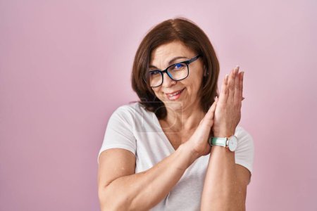 Téléchargez les photos : Middle age hispanic woman standing over pink background clapping and applauding happy and joyful, smiling proud hands together - en image libre de droit